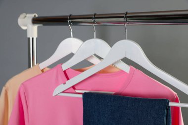 Gri arkaplanda asılı duran farklı şık kıyafetler, yakın plan.