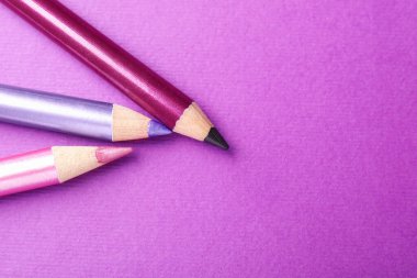 Mor arka planda göz kalemleri, düz yatış. Metin için boşluk