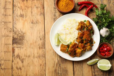 Pirinçli tavuk tikka masala, maydanoz, kireç ve baharatlar ahşap masada, düz yatak. Metin için boşluk