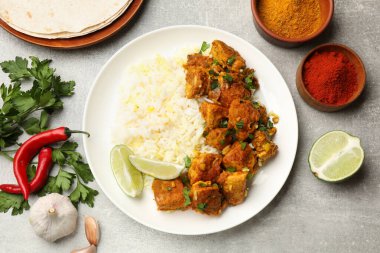 Lezzetli tavuk tikka masala ile pirinç, maydanoz, kireç ve baharatlar gri desenli masa, düz yatak