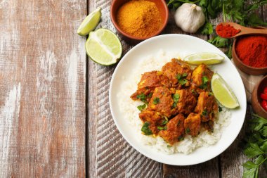 Lezzetli tavuk tikka masala, pirinç, maydanoz, kireç ve baharatlar ahşap masa, düz yatak. Metin için boşluk
