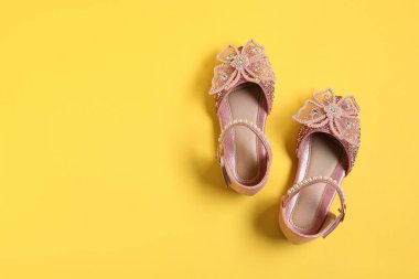 Sarı arka planda bir çift şık çocuk ayakkabısı, düz. Metin için boşluk