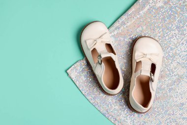 Bir çift şık çocuk ayakkabısı ve açık mavi arka planda parlak kumaş. Metin için boşluk