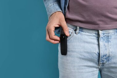 Açık mavi arka planda cebinde gizli kamera olan bir adam, yakın plan. Metin için boşluk