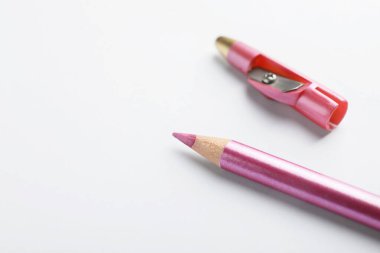 Beyaz arka planda pembe göz kalemi ve keskinleştirici, yakın plan. Metin için boşluk