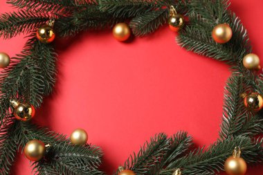 Kırmızı arka planda mücevherleri olan Noel ağacı dallarından yapılmış bir çerçeve. Metin için boşluk