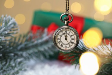 Cep saati, köknar dalları, hediye kutusu ve altın arka planda bulanık ışıklı yapay kar, yakın plan. Yeni yıl tebrik kartı.