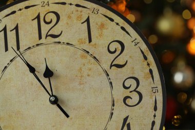 Duvardaki saate karşı karanlık arka plan, bulanık ışıklar, yakın plan. Yeni yıl tebrik kartı.