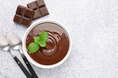 Erimiş çikolatayı kasede nane şekeri, parçaları ve kaşıkları açık gri masada, düz yerde. Metin için boşluk