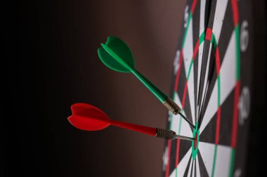 Siyah arka planda dartları olan dart tahtası, yakın plan. Metin için boşluk