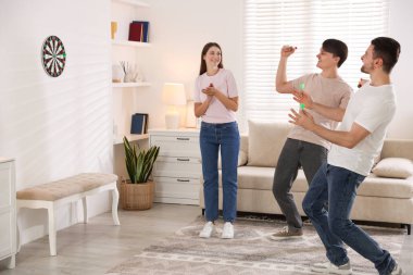 Evde dart oynayan üç mutlu arkadaş.