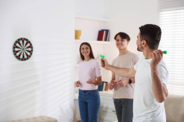 Adam ve arkadaşları evde dart oynuyorlar, seçici bir odaklanma.