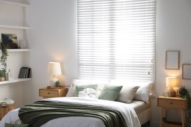 Büyük yataklı, yastıklı, çiçekli ve lambalı şık bir yatak odası. İç tasarım