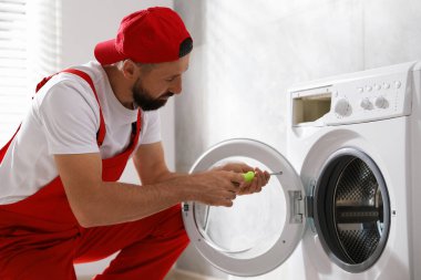 Profesyonel tamirci içeride bozuk çamaşır makinesini tamir ediyor.
