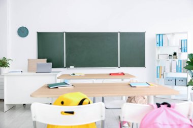 Sınıfta yeşil karatahta, masalar ve sandalyeler var. Tasarım için model