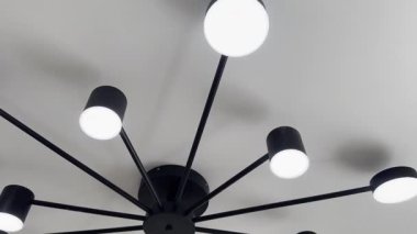 Aydınlatılmış bir avize ve odanın beyaz tavanında raylı aydınlatma.