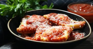 Koyu ahşap masada domates soslu ve peynirli lezzetli ravioli, yakın plan.