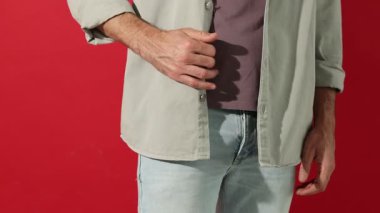 Kırmızı arka planda cebinde gizli kamera olan bir adam, yakın plan. Kamera ileri gidiyor