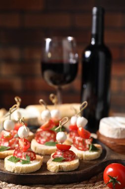 Salamlı nefis bruschettalar, mozzarella ve domatesler masada kırmızı şarapla servis edilir, yakın plan.
