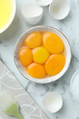 Kırık yumurtalar, yumurtalar, sarılar, beyazlar ve beyaz mermer masa üzerinde fırçalar.