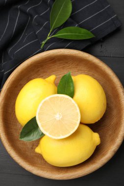 Yeşil yapraklı taze limonlar, siyah ahşap masa, üst manzara.