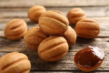 Ahşap masada kaynatılmış konsantre sütle lezzetli fındık şekilli kurabiyeler, yakın plan.