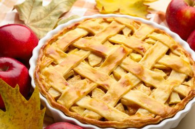 Lezzetli ev yapımı elmalı turta, elmalar ve kuru yapraklar masada, yakın plan.