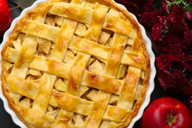 Lezzetli ev yapımı turta, taze elma ve çiçekler masada, düz yerde.