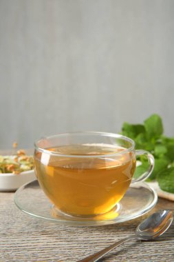 Cam fincanda lezzetli çay ve ahşap masada çay kaşığı gri arka planda, yakın plan. Metin için boşluk