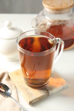 Cam fincanda lezzetli çay ve beyaz masada çay kaşığı, yakın plan.