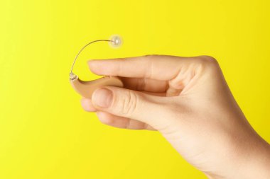 Sarı arka planda işitme cihazı olan kadın, yakın plan. Metin için boşluk