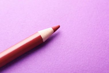 Mor arka planda kırmızı göz kalemi, yakın plan. Metin için boşluk