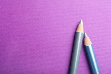 Mor arka planda farklı göz kalemleri, üst manzara. Metin için boşluk