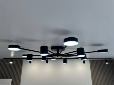 Aydınlatılmış bir avize ve odanın beyaz tavanında raylı aydınlatma.