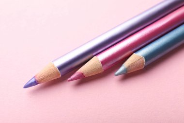 Pembe arka planda farklı göz kalemleri, yakın plan.