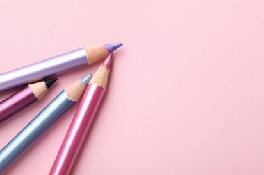 Pembe arka planda parlak göz kalemleri, düz yatış. Metin için boşluk