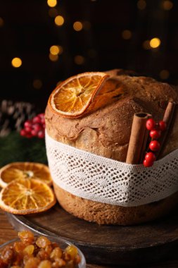 Noel yemeği. Lezzetli Panettone pastası, malzemeler ve arka planda arka planda bulanık ışıklı şenlikli dekor, yakın plan. Bokeh etkisi