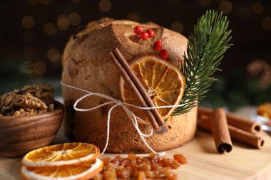 Noel yemeği. Lezzetli Panettone pastası, malzemeler ve arka planda arka planda bulanık ışıklı şenlikli dekor, yakın plan. Bokeh etkisi