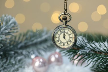 Cep saati, parlak mücevherler, köknar dalları ve bulanık ışıklara karşı yapay kar, yakın plan. Yeni yıl tebrik kartı.