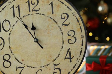 Duvardaki saate karşı karanlık arka plan, bulanık ışıklar, yakın plan. Yeni yıl tebrik kartı.