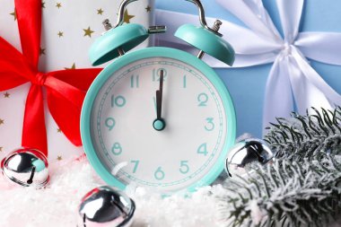 Çalar saat, şenlikli dekor ve yapay kar üzerinde hediye kutuları, yakın plan. Yeni yıl tebrik kartı.