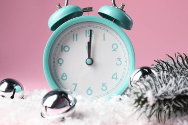 Alarm saati ve pembe arka planda şenlikli dekor, yakın plan. Yeni yıl tebrik kartı.