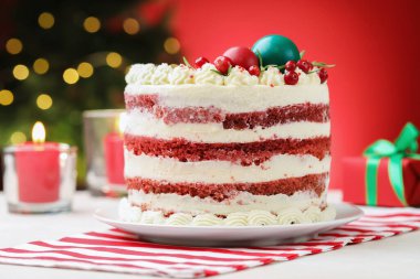 Kırmızı arka planlı, kırmızı ışıklı, Noel dekorlu leziz bir kek. Yakın plan. Bokeh etkisi