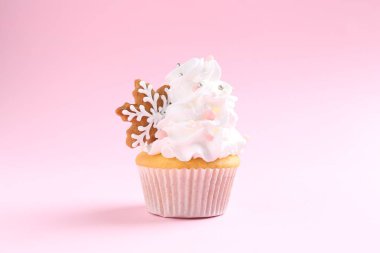 Soluk pembe arka planda Noel dekoru olan lezzetli kek, yakın plan.