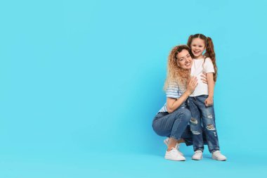 Mutlu anne açık mavi arka planda kızına sarılıyor. Metin için boşluk