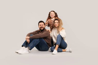 Mutlu ebeveynler ve gri arka planda poz veren kızları. Aile bağı