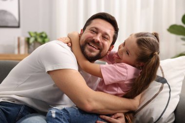 Mutlu bir babanın evdeki kanepede kızını kucaklaması. Aile bağı