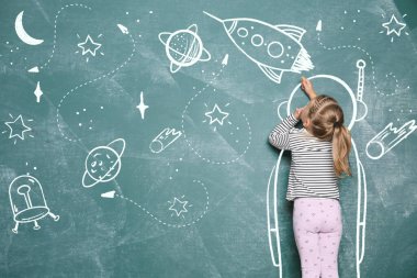 Yeşil karatahtaya beyaz tebeşirle çizen küçük çocuk. Kız kendini astronot olarak hayal ediyor.