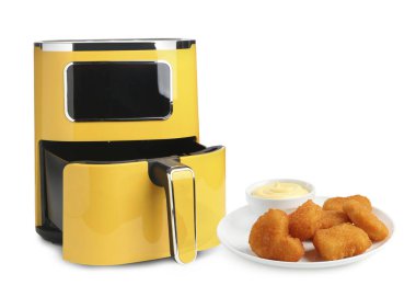 Sarı kızartma makinesi ve beyaz arka planda pişmiş tavuk nugget.