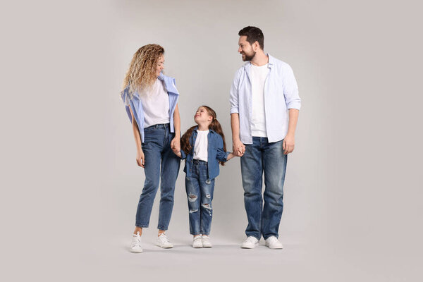 Счастливая семья держится за руки на сером фоне